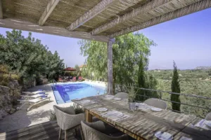 Dining table under the reed pergola at Villa Levanda, overlooking the pool